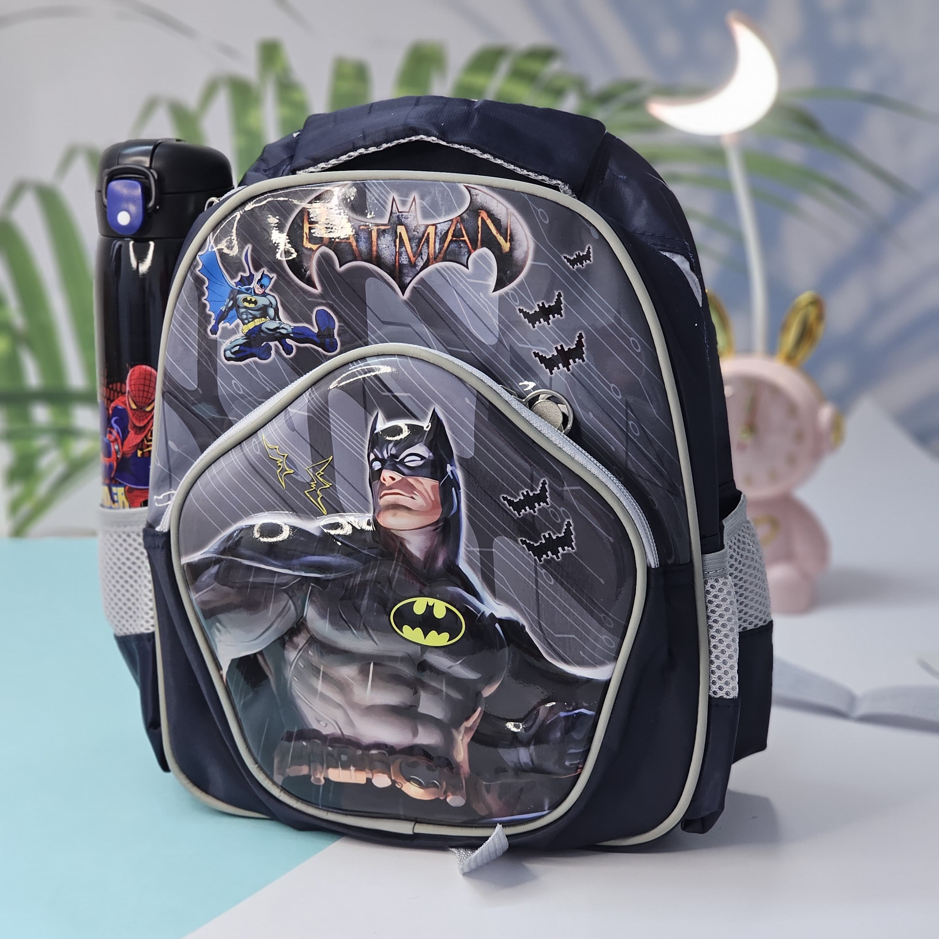 Batman-themed backpack on a light blue surface with a blurred background